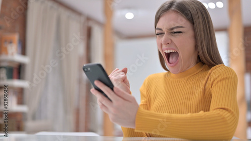 Beautiful Young Woman Celebrating Success on Smartphone