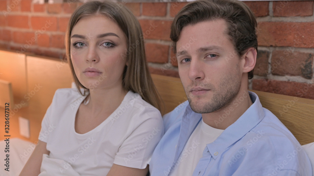 Obraz premium Young Couple Looking in Camera from Bed