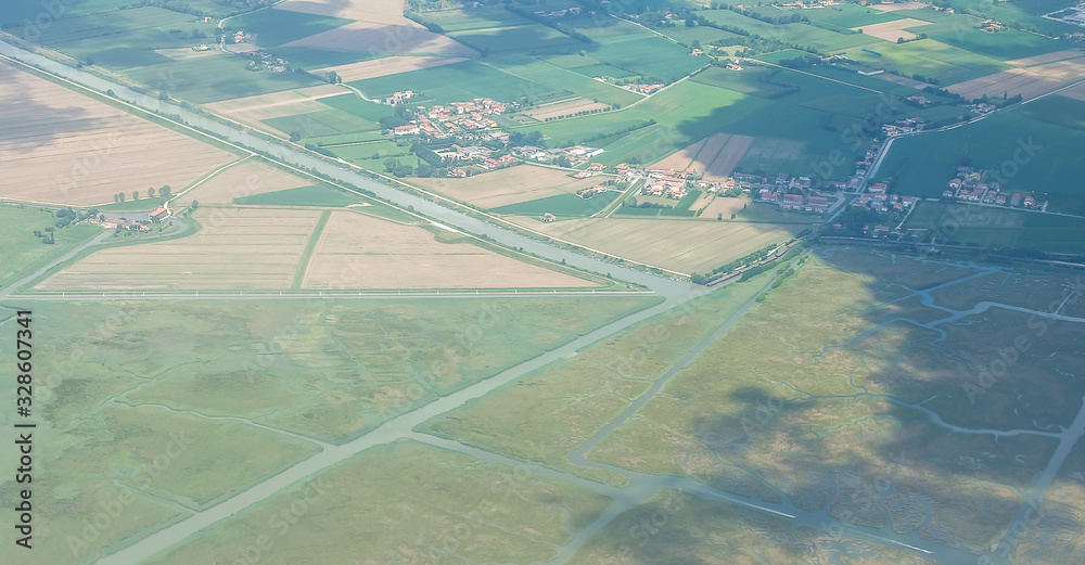 Aerial view from the plane over cities, with roads, river, forests, meadows, rural fields