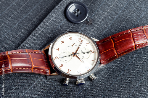 male wristwatch made of silver case and brown leather strap, close up watches with by the gray strict suit, nobody.