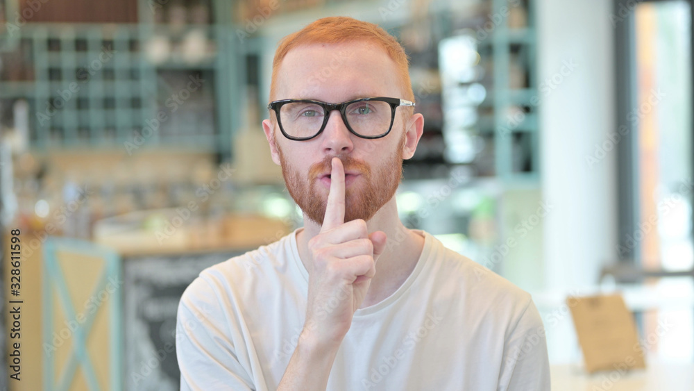 Naklejka premium Portrait of Young Redhead Man with Finger on Lips, Quiet