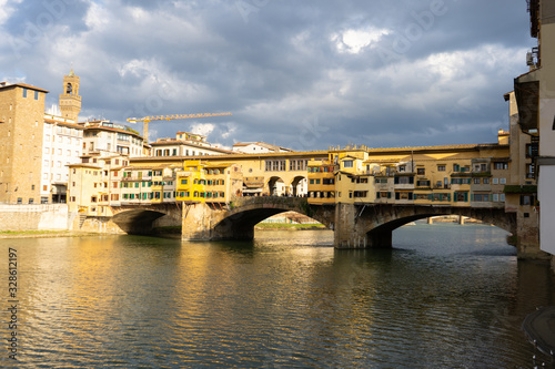 Ponte Vecchio in Florence by day, with the lights reflecting in the water
