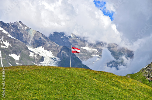 The Grossglockner (German name is Großglockner)  highest mountain in Austria and the highest mountain in the Alps east with Austria Flag and Cloud in summer.