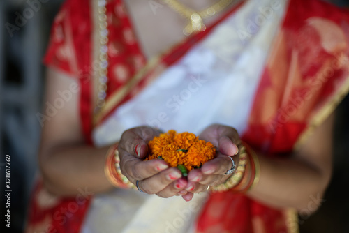 An Indian Bengali lady in bengali ethnic and traditional dress offering orange flowers as homage holding in her palms. Indian culture and lifestyle. photo