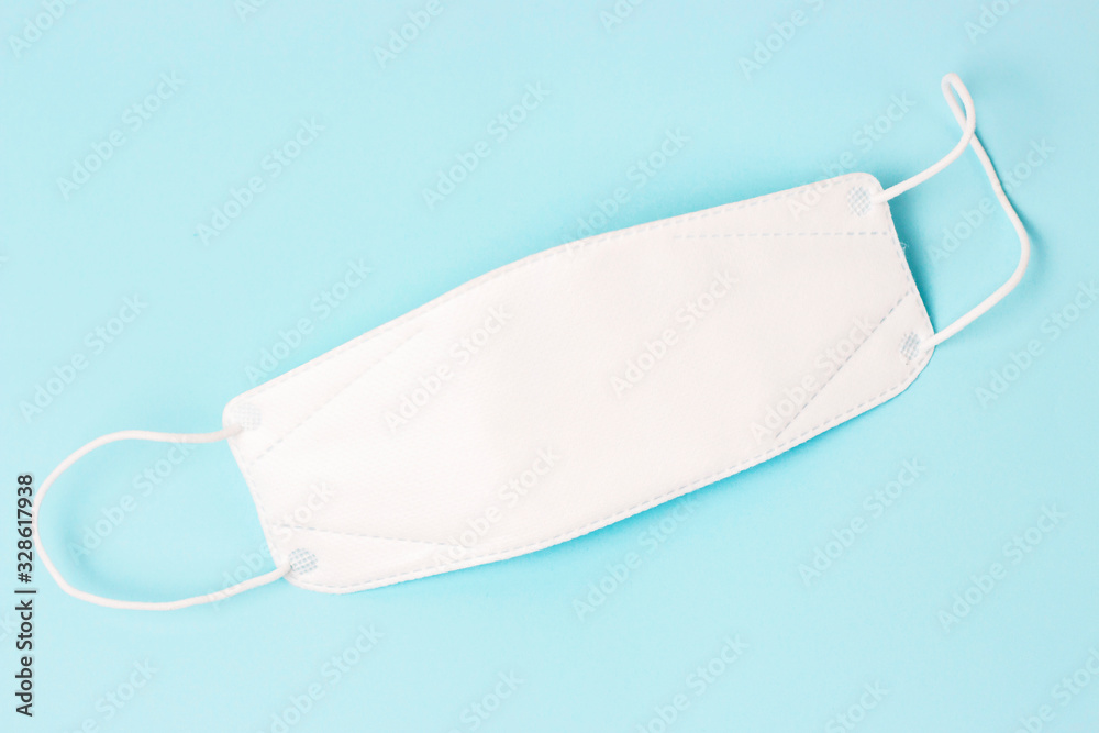 Protective white mask on blue background, close-up, top view. Protective white mask on blue background, close-up, top view.