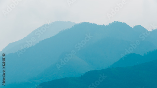 Fototapeta Naklejka Na Ścianę i Meble -  silhouettes of mountains in blue haze. Outline of gentle hills in the valley