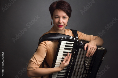 A brunette in a gold shirt, with a short haircut, on a light gray background of the Studio. With accordion musician