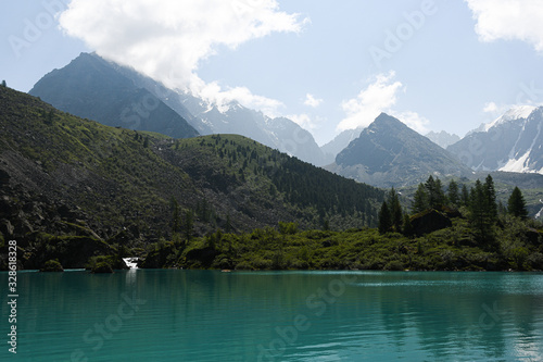 lake in mountain valley, surface of water under rocky peaks, mountain surface on horizon, path to top and its achievement by river