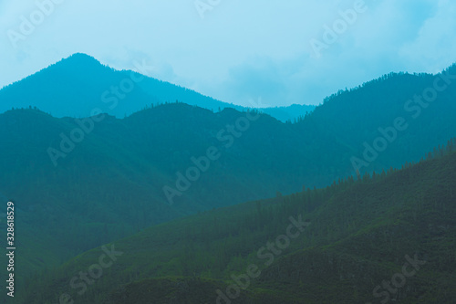 silhouettes of mountains in blue haze. Outline of gentle hills in the valley