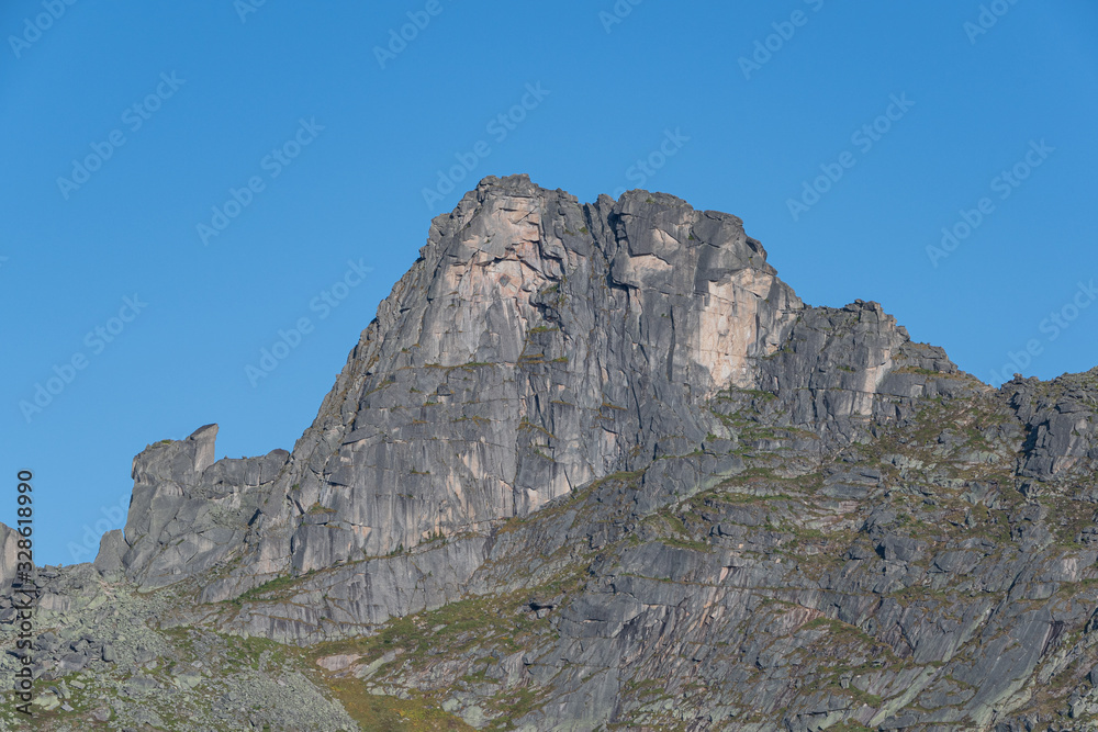 rocky ridge under blue sky in mountain valley, journey of climbers on sheer cliffs rocky ridge under blue sky in mountain valley, journey of climbers on sheer cliffs