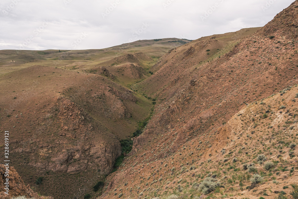 gentle red hills, journey through mountain valley, pastures for animals, soil erosion in arid steppe gentle red hills, journey through mountain valley, pastures for animals, soil erosion in arid steppe
