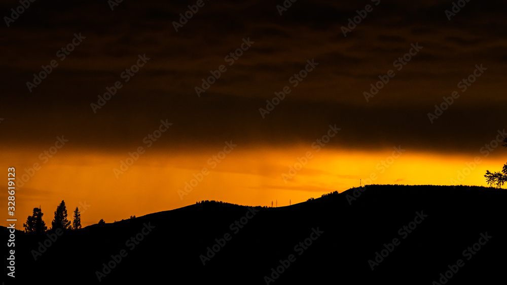 orange sunset and clouds over silhouette of mountain range