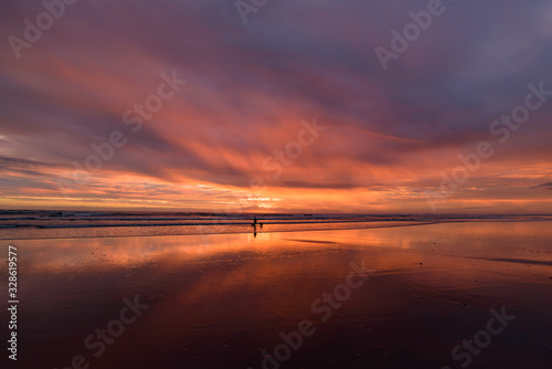 Muriwai Beach at sunset time with colorful clouds, New Zealand