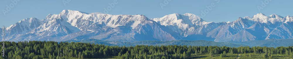 Wide panorama of the ridge. Forest and snow-capped peaks, sunny summer morning.