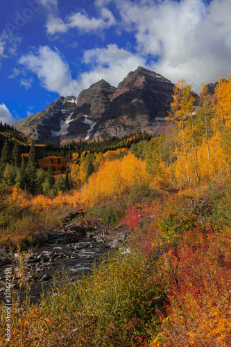 Maroon bells peaks through colorful trees in Colorado photo
