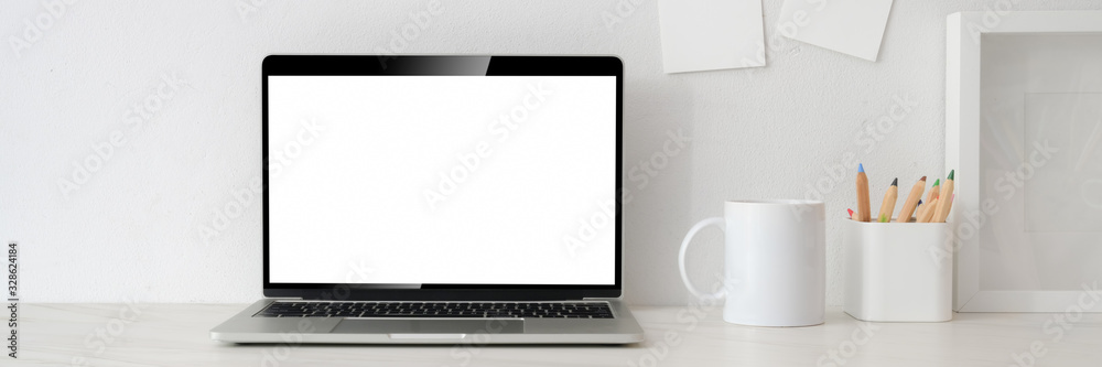 Cropped shot of workspace with blank screen laptop, white mug, stationery and decorations on white table - obrazy, fototapety, plakaty 