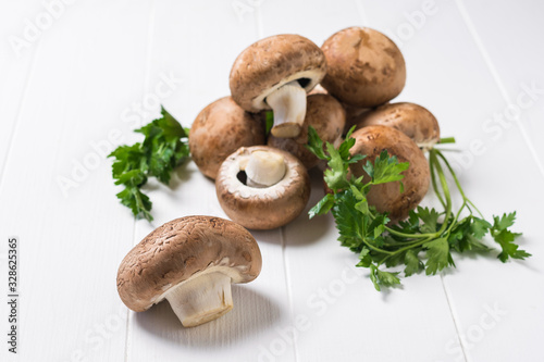 Several Royal mushrooms with parsley leaves on a white wooden table. Vegetarian food.