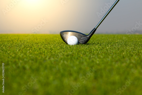 Golf club and ball in grass at the Golf course. White Golf ball on Green field golf course in morning time with sun light