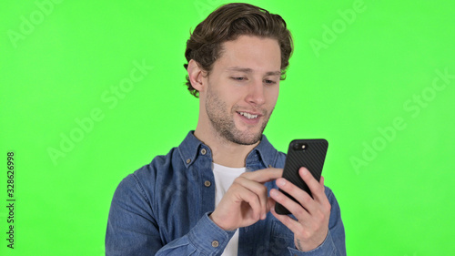 Portrait of Young Man using Smartphone on Green Chroma Key