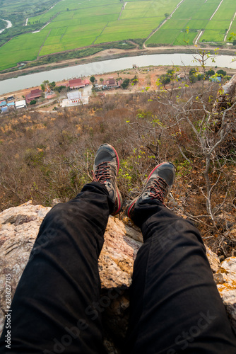 Legs of traveler sitting on  high mountain cliff