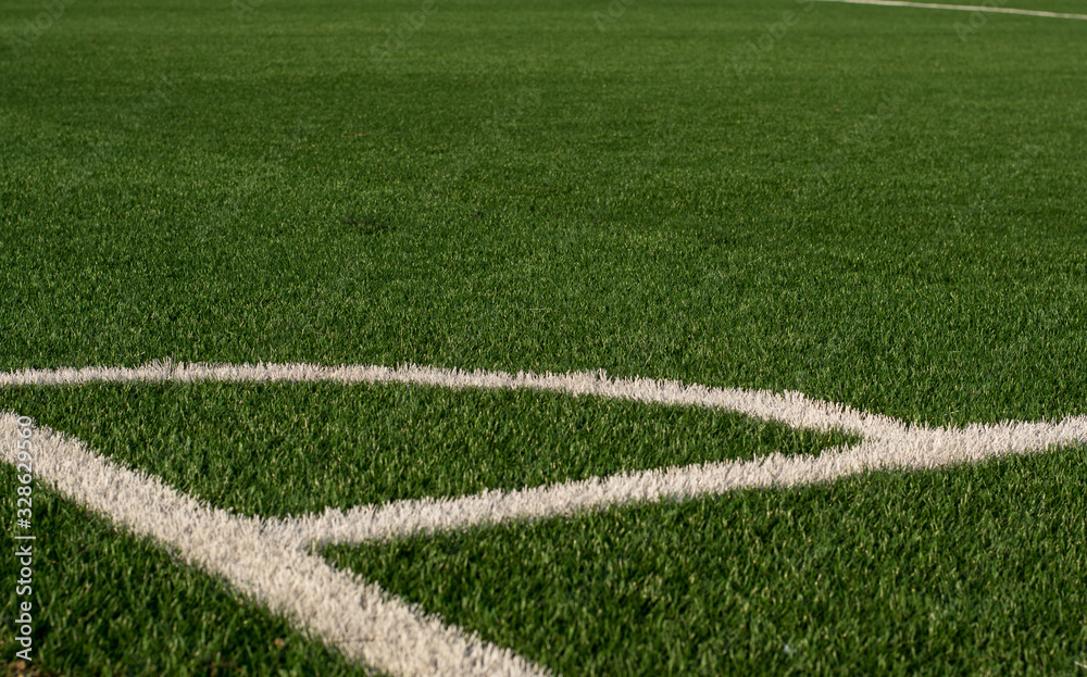 Artificial green grass and white border lines. Artificial turf for soccer field. Football field in an outdoor stadium. Selective focus