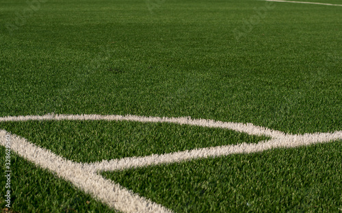 Artificial green grass and white border lines. Artificial turf for soccer field. Football field in an outdoor stadium. Selective focus