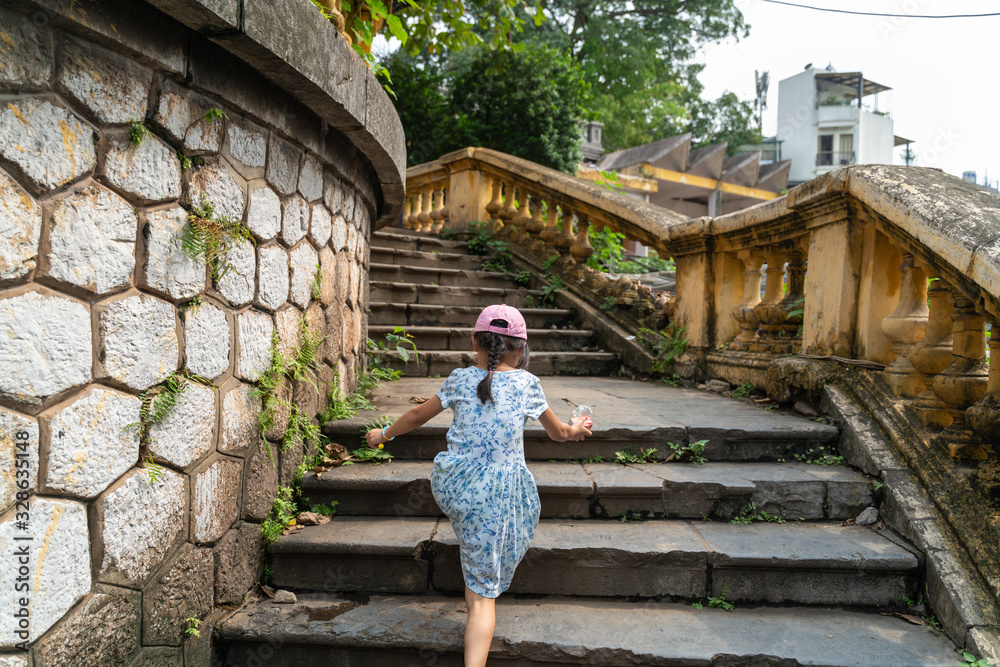 Old open outer stone staircase, aged footpath in Hanoi city with a child running up on steps