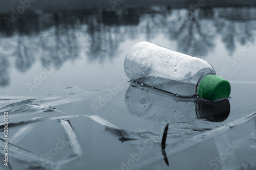 Fototapeta Naklejka Na Ścianę i Meble -  A plastic bottle floating in river at the water, environmental problem with plastics pollution lakes and rivers, polluting water. Plastic garbage in the river or lake. litter in water