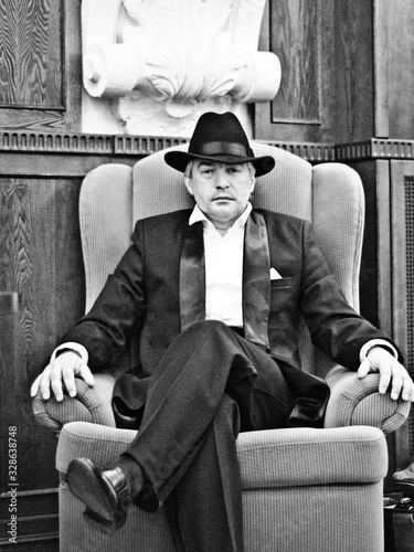A grey-haired elderly mobster in an interior.