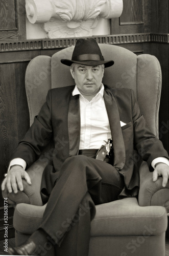 A grey-haired elderly mobster in an interior.