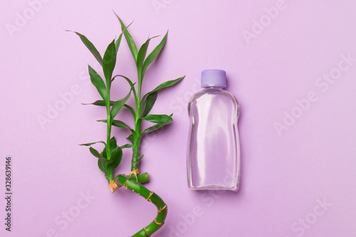 purple cosmetic bottle with bamboo stalk on purple background