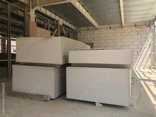 Piled sheets of drywall at the construction site. Stacked plasterboard sheets. Gypsum cardboard