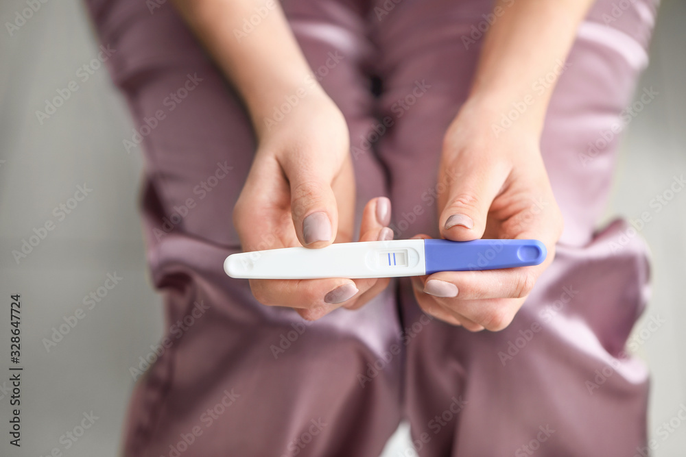 Young woman with pregnancy test in bathroom, closeup