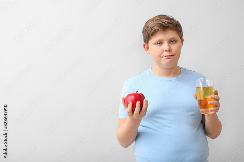 Overweight boy with apple and juice on light background Overweight boy with apple and juice on light background