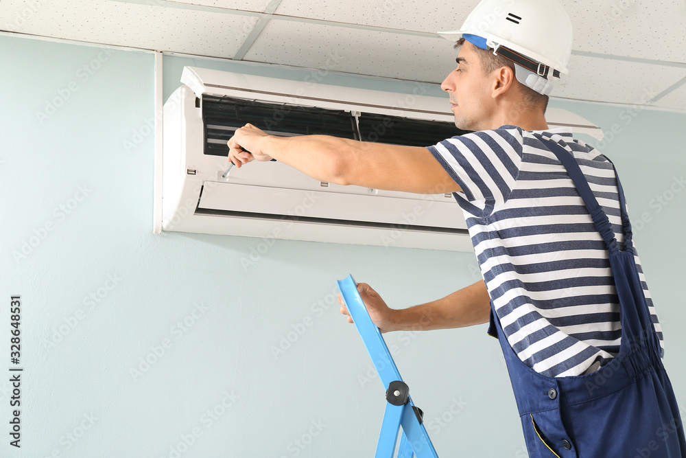 Male technician repairing air conditioner indoors Male technician repairing air conditioner indoors