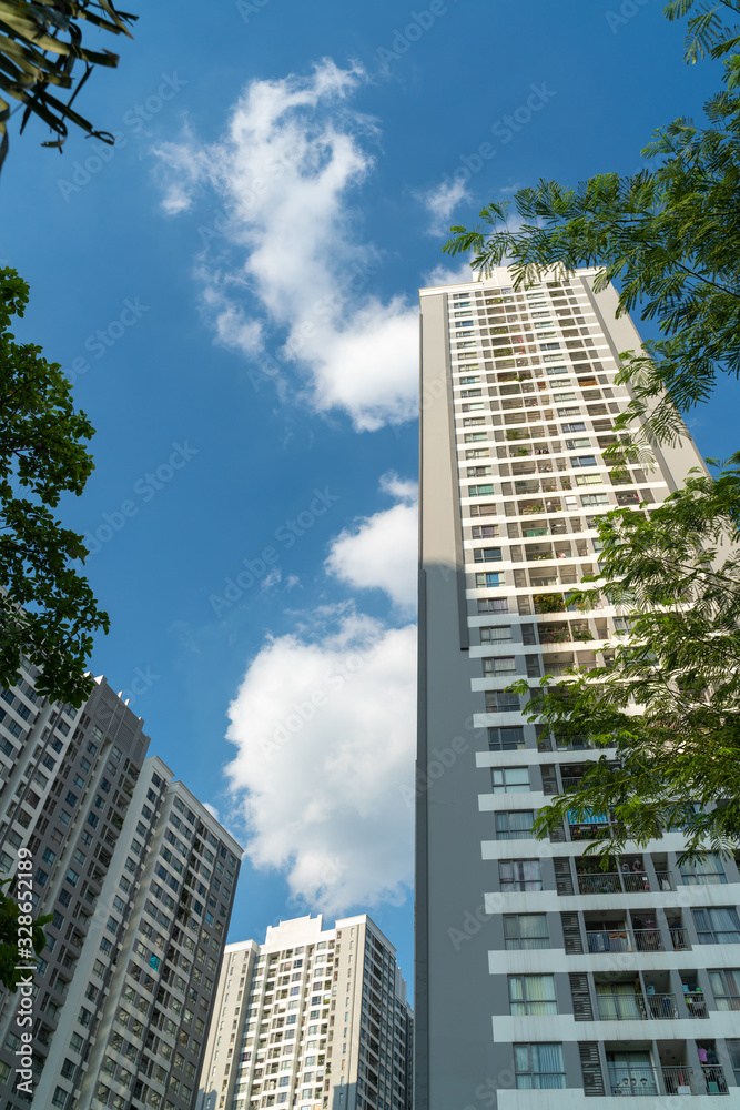Modern condominium building with green leaves on foreground. Green city concept