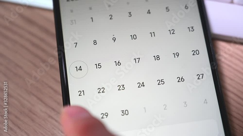 Close-up of a man's hand using a smartphone calendar application.