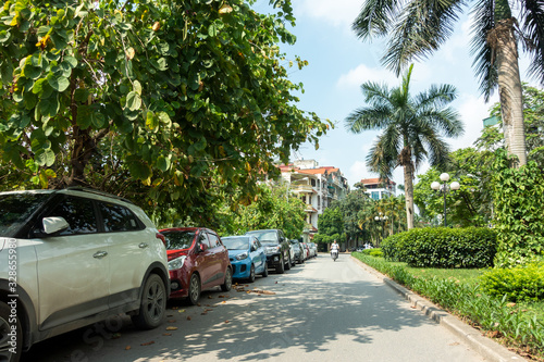 Parallel cars parking on street with green trees © Hanoi Photography