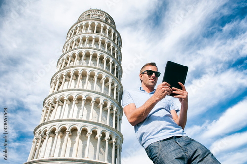 Tourist leaning against the Tower of Pisa using a tablet photo