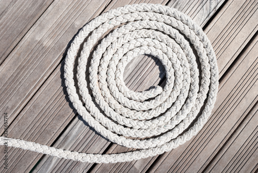 Obraz premium Thick white nautical rope forming a spiral outdoors on a weathered wood dock