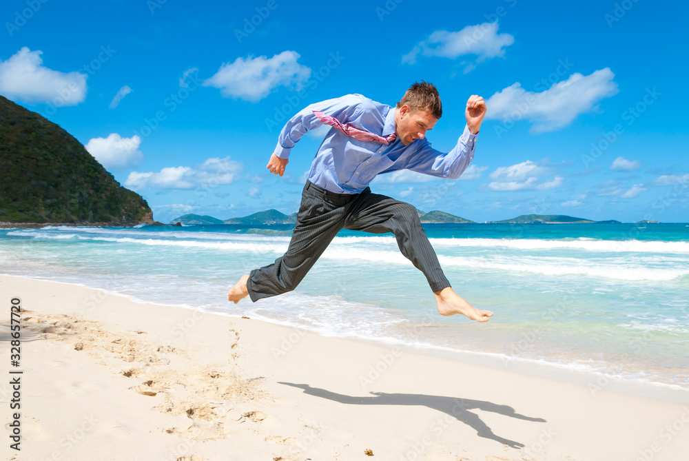 Barefoot businessman jumping across an empty tropical beach Barefoot businessman jumping across an empty tropical beach