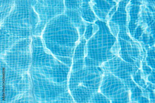 Photo of water in swimming pool, surface of blue pool, ripple vacuity in pool, sun reflection in basin, clear light blue pool water, top view of backwash in basin, rippled aqua detail background.