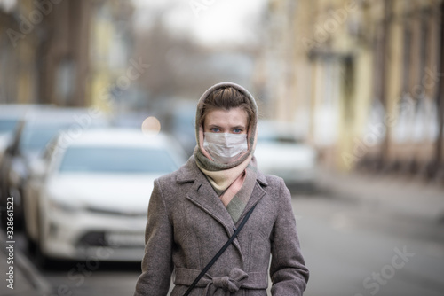 Young attractive woman outdoors in a medical protective mask. Protection against viruses - influenza, coronavirus and others