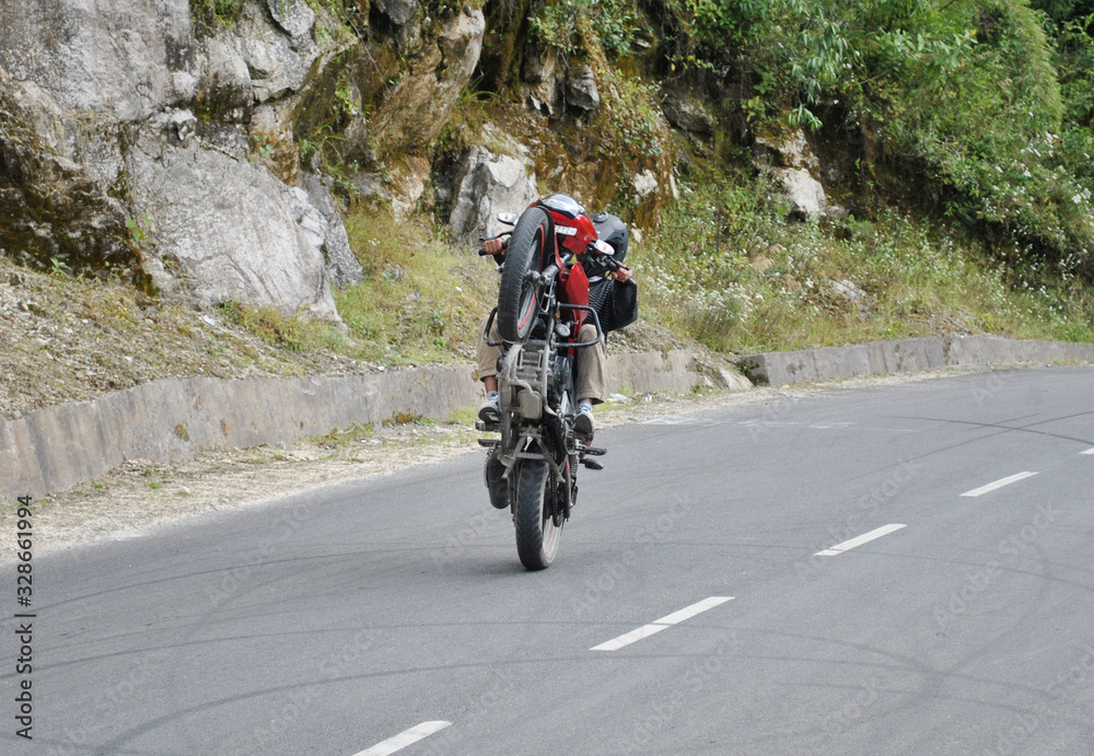 Man practicing bike stun at narrow gauge Bulbulay road in Gangtok, Sikkim. Usually in their free times guys comes here, they learn and practice bike stun. They get inspired from YouTube and others. Man practicing bike stun at narrow gauge Bulbulay road in Gangtok, Sikkim. Usually in their free times guys comes here, they learn and practice bike stun. They get inspired from YouTube and others.