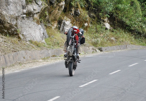 Man practicing bike stun at narrow gauge Bulbulay road in Gangtok  Sikkim. Usually in their free times guys comes here  they learn and practice bike stun. They get inspired from YouTube and others.