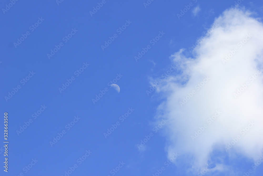 Young month against the blue sky with a small white cloud. Young month against the blue sky with a small white cloud.