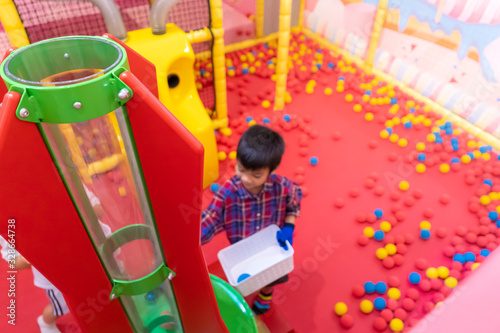 Littke asian kid is having fun playing with ball cannnon in Indoor playground photo