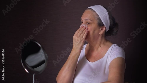 Mature woman use cosmetic discs to clean face after bath