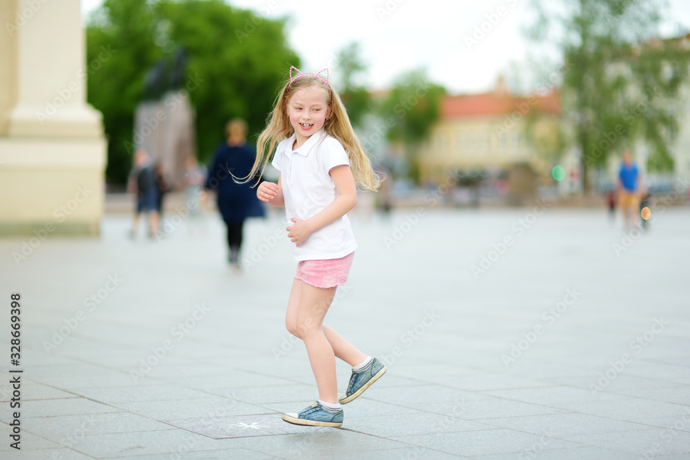 Cute young girl sightseeing on the streets of Vilnius, Lithuania on warm and sunny summer day.