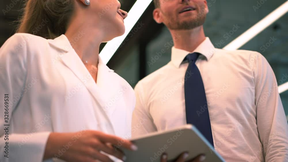 Confident female executive manager in formal wear holding modern touch pad in hands and discussing ideas with experienced male colleague, digital tablet for business using Confident female executive manager in formal wear holding modern touch pad in hands and discussing ideas with experienced male colleague, digital tablet for business using